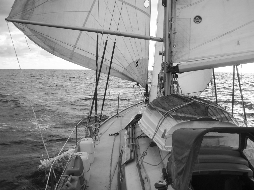 Wing 'n' wing across the Pacific aboard our simple boat. Note the tiny sprayhood and the rowing dinghy - traditional seamanship